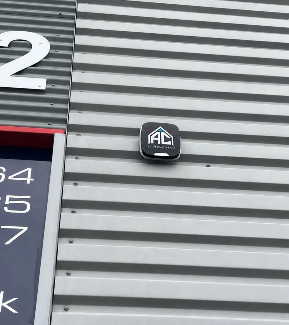 External alarm siren with the AC Home Tech logo on an industrial unit