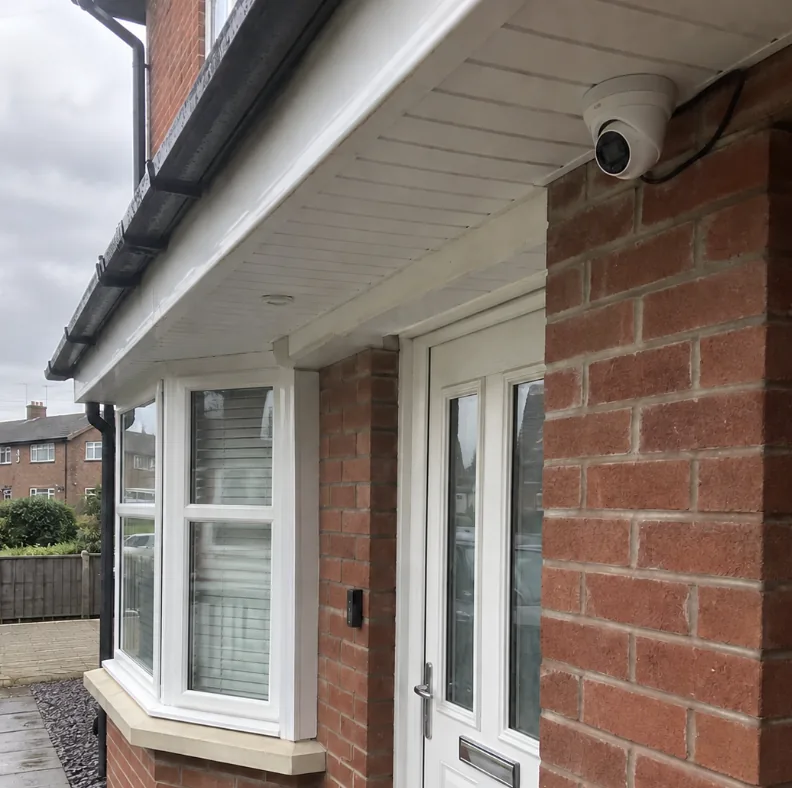 CCTV camera installed beside a front door on a brick house