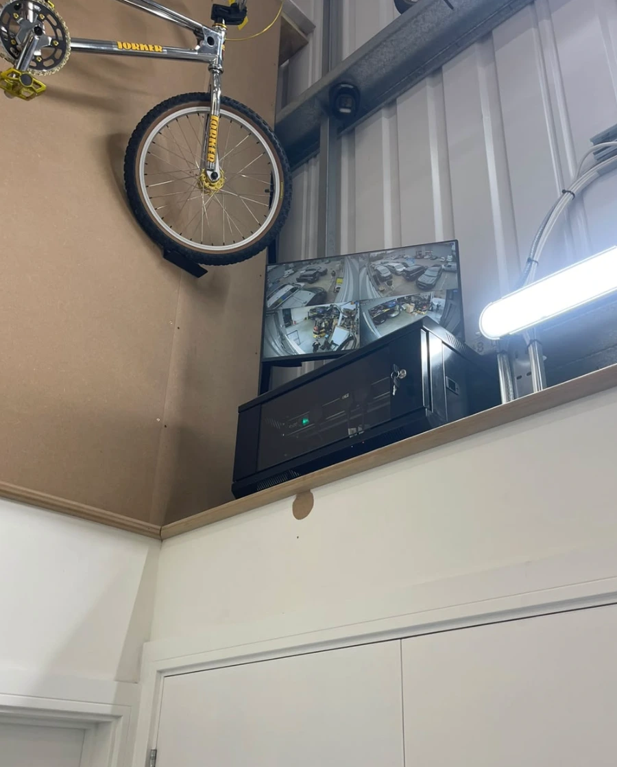 CCTV recorder in a locked cabinet with a monitor showing live camera feeds in a workshop