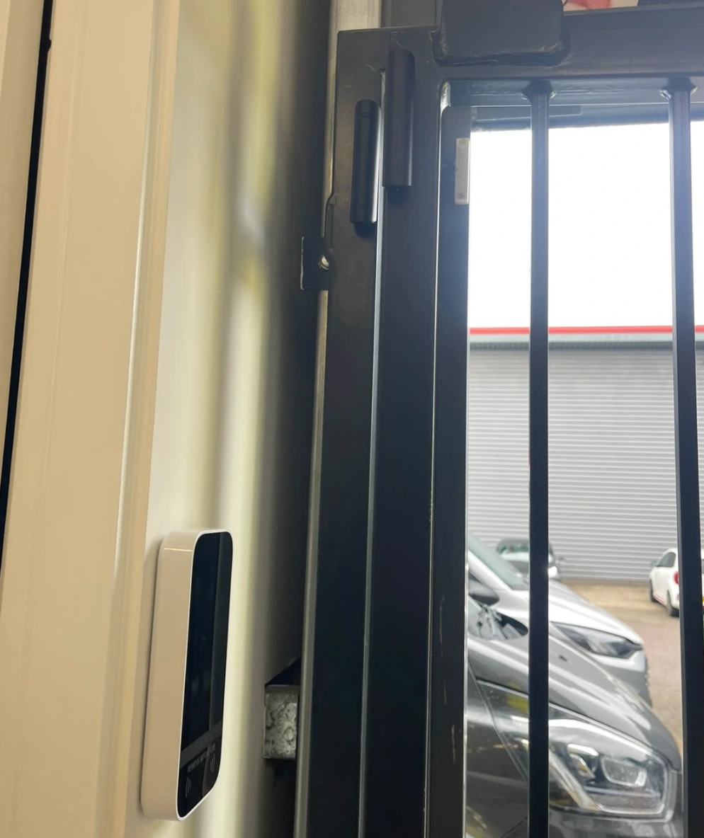 Access control reader on the wall beside a steel security gate