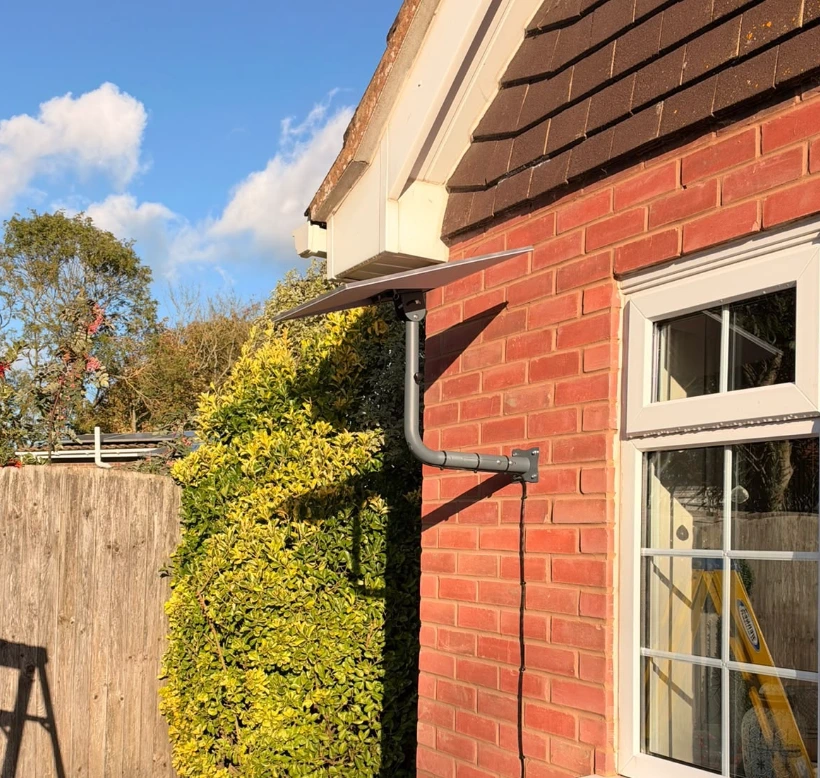 Starlink dish mounted on a wall bracket on a brick house